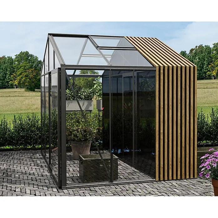 Bloomcabin Gewächshaus Aluminium Klassik mit Accoya-Fusion und kleinem integrierten Stauraum - Außenmaß inkl. Dachüberstand (B x T): 309 x 235 cm, Material Seitenwand: Glas, 4 mm, Schwarz - Modernes Gewächshaus mit dunklem Metallrahmen, Glaspaneelen und Holzlamellen an Seite/Dach, auf einer Terrasse im Garten.