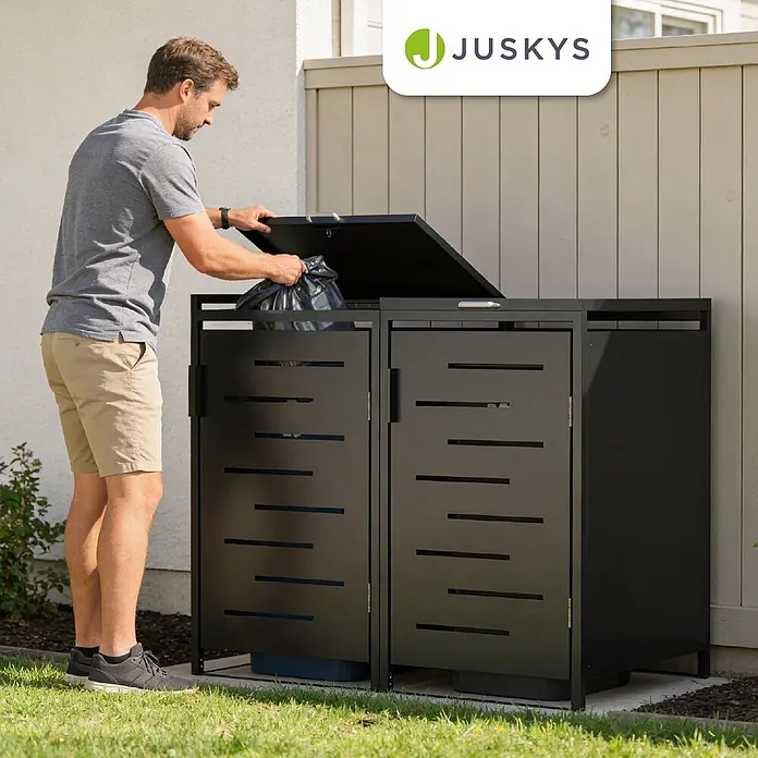 Juskys Mülltonnenbox Arel - 136 x 80 cm, Metall, Anthrazit, Geeignet für Anzahl Mülltonnen: 2 Stk. - Mann legt Müllsack in schwarzen Metall-Mülltonnen-Aufbewahrungsschrank im Garten, der Abfallbehälter verdeckt.