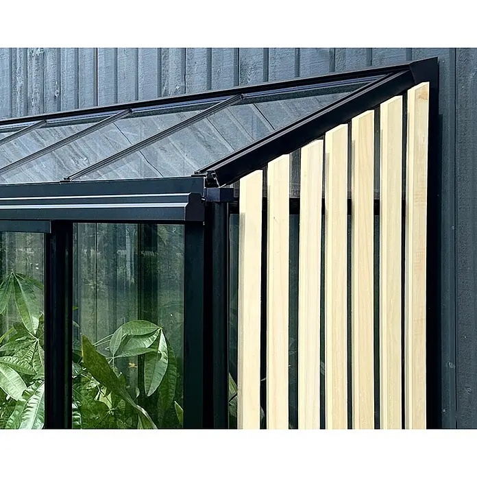 Bloomcabin Gewächshaus Aluminium Mini mit Accoya-Fusion - Außenmaß inkl. Dachüberstand (B x T): 120 x 66 cm, Material Seitenwand: Glas, 4 mm, Schwarz - Ecke eines schwarz gerahmten Gewächshauses mit Glasdach, vertikalen Holzlamellen zur Beschattung und grünen Pflanzen darin.