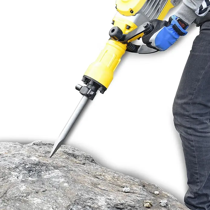 Bamato Abbruchhammer STH-195 inkl. 7-tlg. Zubehörset - 1.700 W, 50 J, SDS-Hex-Aufnahme - Gelber und silberner Abbruchhammer, der von einer Person mit Handschuhen zum Brechen eines Felsens verwendet wird.