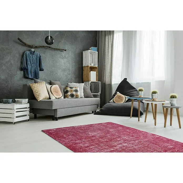 Kayoom Kurzflorteppich Etna - Melone, 230 x 160 cm, 100 % Mikropolyester - Wohnzimmer mit einem roten Teppich, einem grauen Sofa und einem Sitzsack. Der Teppich ist das zentrale Element des Raumes.