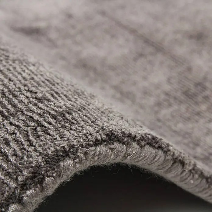 Kayoom Kurzflorteppich Luxury 110 - Grau, 150 x 80 cm, 100 % Viskose - Nahaufnahme eines grauen Teppichs, der die Textur und Verarbeitung des Teppichs hervorhebt. Ideal für die Inneneinrichtung.
