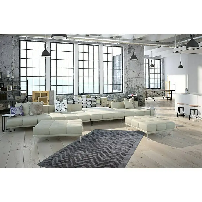 Kayoom Kurzflorteppich Luxury 410 - Grau, 170 x 120 cm, 100 % Viskose - Ein modernes Wohnzimmer mit einem modularen cremefarbenen Sofa, einem grauen Teppich mit Zickzackmuster und großen Fenstern für viel Tageslicht.