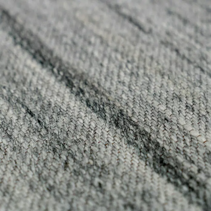 Kayoom Flachgewebeteppich Phönix - Grau, 290 x 200 cm, 75 % Wolle, 20 % Baumwolle, 5 % Polyester - Nahaufnahme eines grauen Teppichs mit subtilen dunklen Streifen, die eine weiche und strukturierte Oberfläche zeigen.