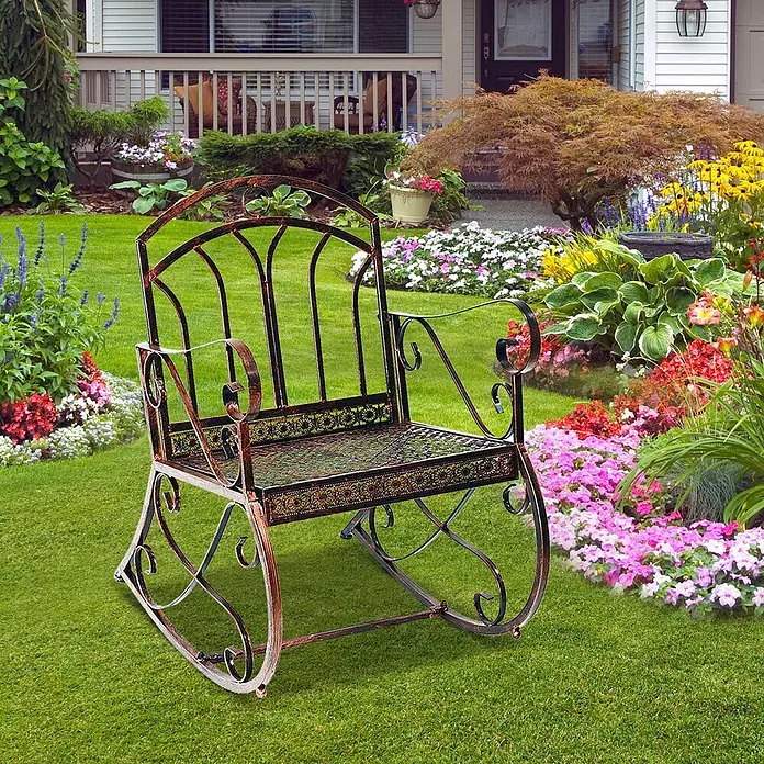 Outsunny Garten-Schaukelstuhl - 1 Stk., Metall, Bronze, B x T x H: 76 x 76 x 90 cm - Ein verzierter Schaukelstuhl aus dunkelbronzenem Metall auf grünem Rasen in einem blühenden Garten.