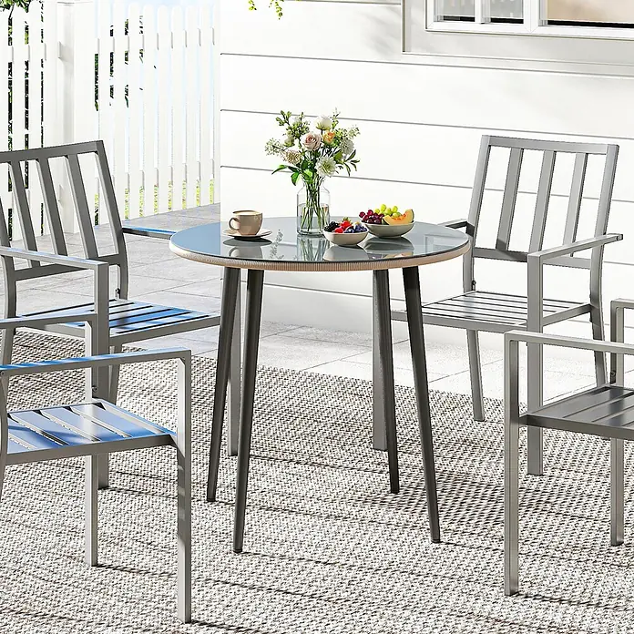 Outsunny Gartentisch rund - gehärtetes Glas, Grau - Graues Outdoor-Esszimmer-Set aus Metall: runder Glastisch mit Rattanbesatz und vier passenden Stühlen auf einem Terrassenteppich.
