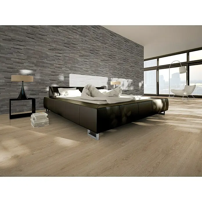 Indo Wandpaneel 3D Wall Driftwood Salis Sea - Hevea, 560 x 200 x 10 mm, 1,008 m² - Schlafzimmer mit großem Bett, Holzfußboden und Steinwand. Das moderne Design des Zimmers wird durch die großen Fenster unterstrichen.