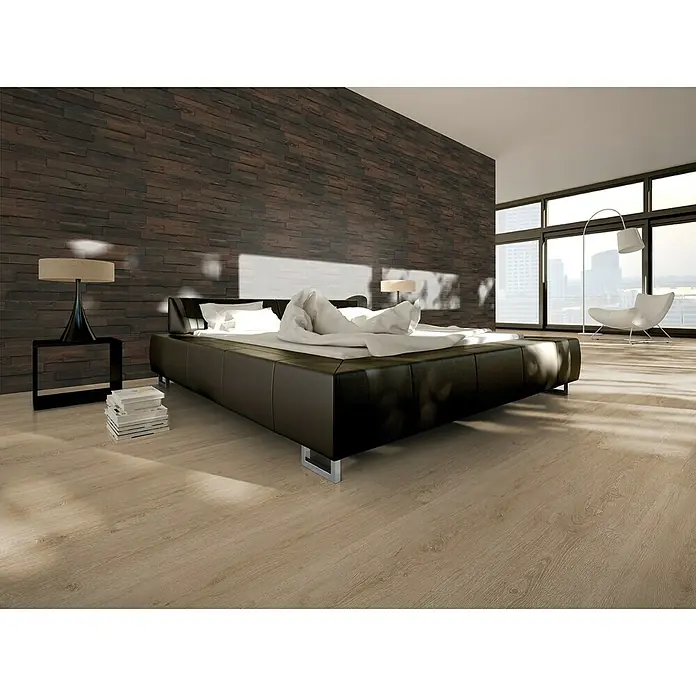 Indo Wandpaneel 3D Wall Driftwood Solomon Sea - Hevea, 560 x 200 x 10 mm, 1,008 m² - Schlafzimmer mit großem Bett, Nachttischlampe und Bücherstapel vor einer markanten Steinwand, die eine moderne und gemütliche Atmosphäre schafft.