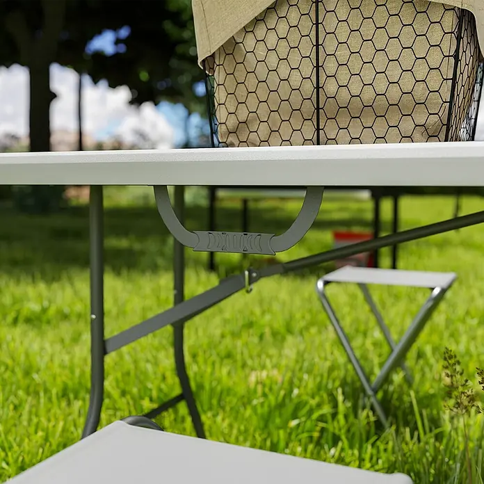 Outsunny Campingtisch - L x B x H: 180 x 74 x 74 cm, HDPE, Weiß - Nahaufnahme eines grauen, tragbaren Klapptisches mit Tragegriff, draußen mit Picknickkorb und Klappstühlen.