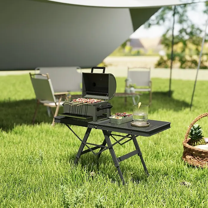 Outsunny Campingtisch - L x B x H: 90 x 40,5 x 58 cm, Schwarz - Schwarzer tragbarer BBQ-Grill und Klapptisch, mit Spießen auf dem Grill und einem Getränk auf dem Tisch.