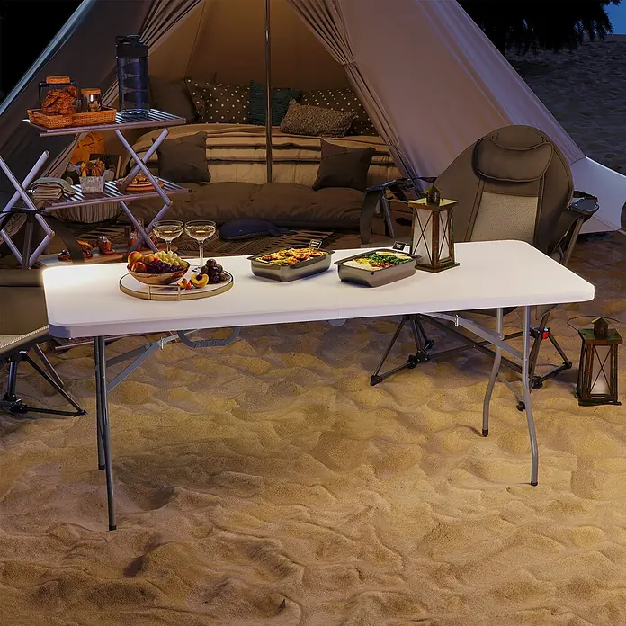 Outsunny Campingtisch - L x B x H: 180 x 74 x 74 cm, HDPE, Weiß - Weißer Klapptisch mit grauen Metallbeinen, für Essen im Freien im Sand aufgestellt.