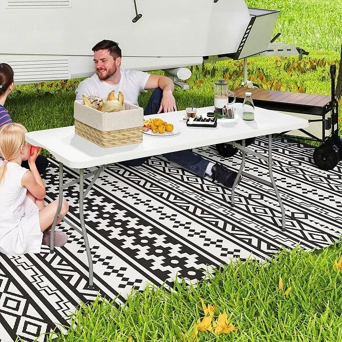Outsunny Campingtisch - L x B x H: 180 x 74 x 74 cm, HDPE, Weiß - Weißer Klapptisch für ein Familienessen im Freien, mit Speisen und Getränken, auf einer gemusterten Matte.