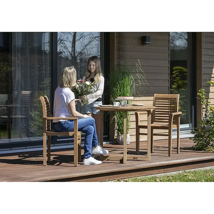 Gartenmöbelset Stapelsessel Derby & Tisch Retford -  - Hölzernes Outdoor-Essset mit rundem Tisch und zwei Stühlen auf einer Terrasse, in Gebrauch gezeigt.