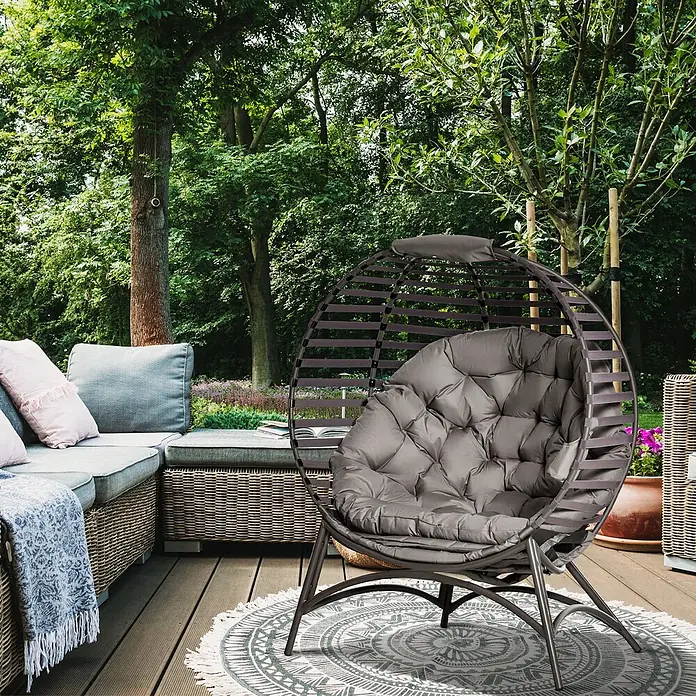 Outsunny Garten-Loungesessel - Sand - Dunkelgrauer Outdoor-Eiersessel mit plüschigem grauen Kissen auf einer Terrasse im Grünen.