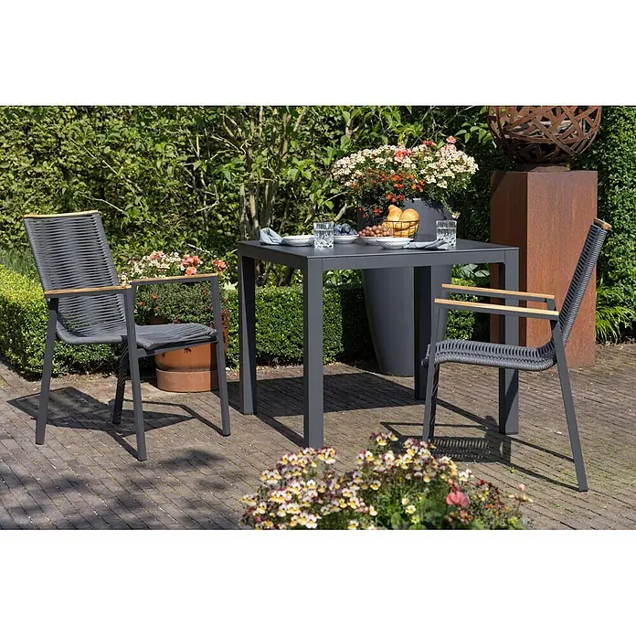 Bene Living Gartentisch-Set Alicante anthrazit mit Tisch Tarifa - Gesamtumfang: 3 -tlg., Aluminiumgestell mit Keramik-Tischplatte, Rope-Geflecht und Teakholz-Armlehnen, Stapelbar - Dunkelgraue Outdoor-Essgruppe mit zwei Stühlen aus geflochtenem Seil und einem Metalltisch auf einer Terrasse. Die Stühle haben Holzarmlehnen.