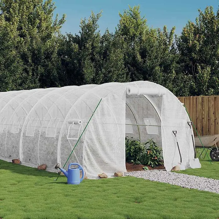 Furnicato Gewächshaus - 10 x 3 cm, Material Seitenwand: Kunststoff, 38 mm, Grau - Weißes Folientunnel-Gewächshaus im Garten, mit Pflanzen im Inneren und Gartengeräten daneben.