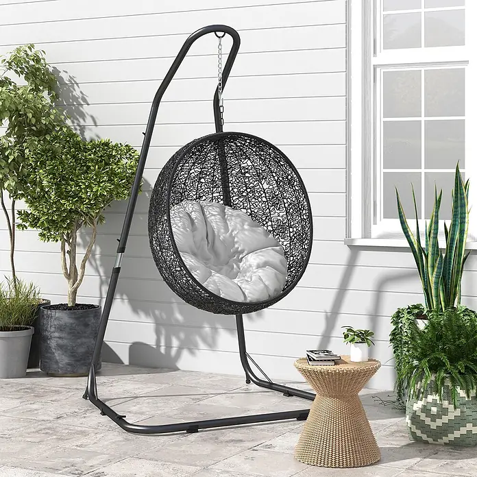 Outsunny Hängesesselgestell - L x B x H: 133 x 116 x 230 cm, Metall - Schwarzer Outdoor-Hängesessel aus Rattan mit weißem Kissen auf einer Terrasse.