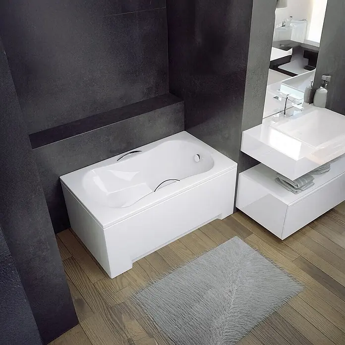 Bad Land Badewanne - 120 x 70 cm, Sanitäracryl, Weiß - Weiß moderne Badewanne mit Chromgriffen in einem dunkel gefliesten Badezimmer neben einem Waschtisch installiert.