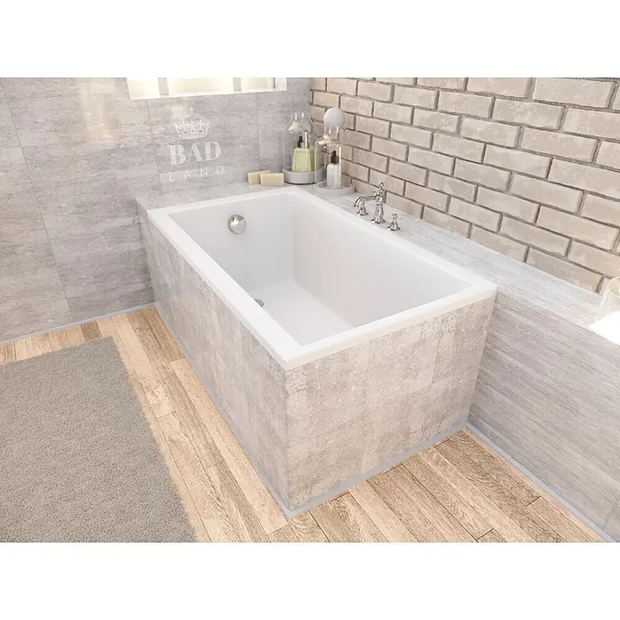Bad Land Badewanne CAPRI Acryl-Eckwanne 100 x 70 cm Weiß - Sanitäracryl, Weiß - Weiße Einbauwanne mit Chromarmaturen, umgeben von hellgrauen Fliesen, einer Ziegelwand und Holzboden in einem modernen Badezimmer.