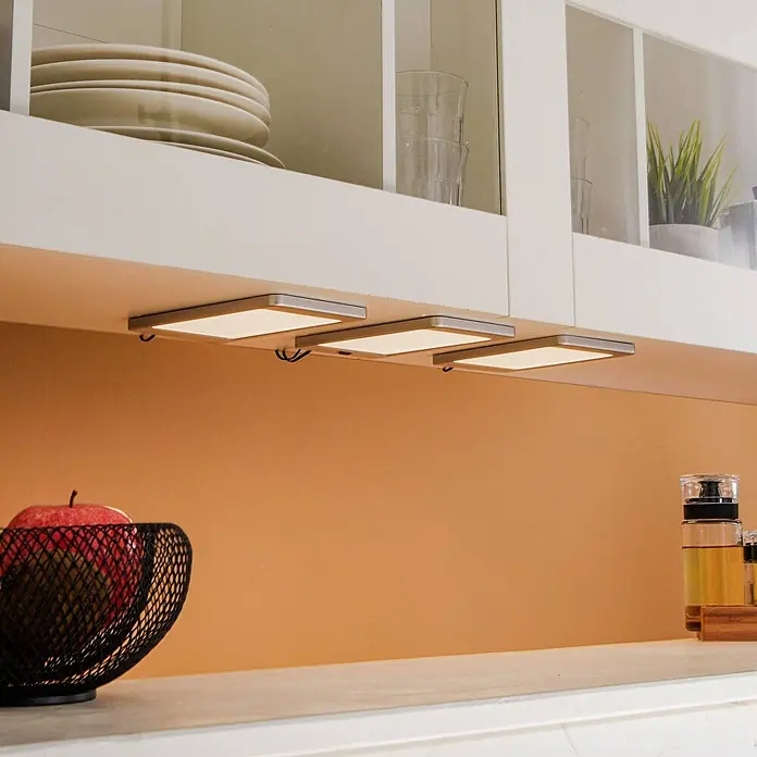 Lindby LED-Unterbauleuchte Svela -  - Drei rechteckige LED-Unterbauleuchten mit silbernen Rahmen, die eine Küchenarbeitsplatte und den Fliesenspiegel beleuchten.