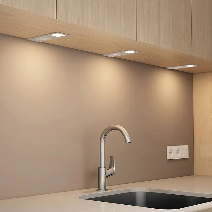 Arcchio LED-Unterbauleuchte Nortra -  - Silberne, rechteckige Unterschrank-LED-Leuchten beleuchten eine Küchenarbeitsplatte und Spüle.