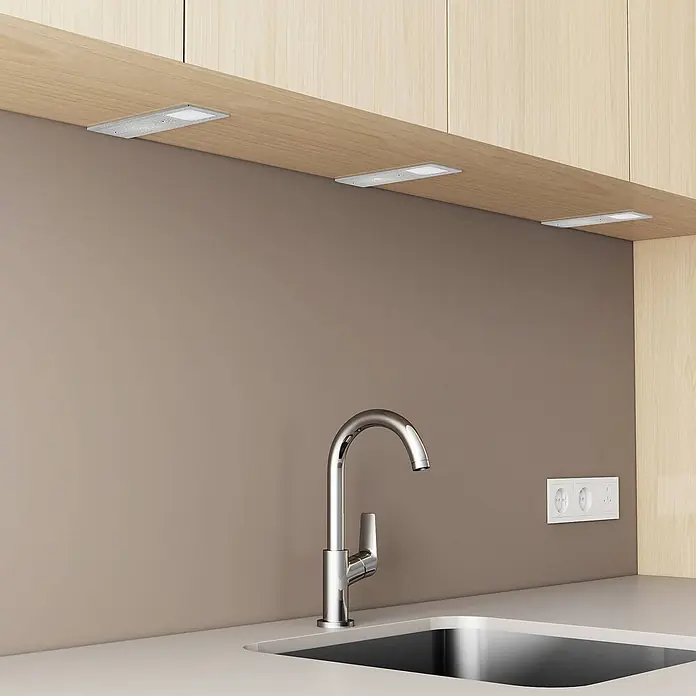Arcchio LED-Unterbauleuchte Nortra -  - Silberne LED-Unterbauleuchten in einer modernen Küche, beleuchten Arbeitsplatte und Spülbereich.