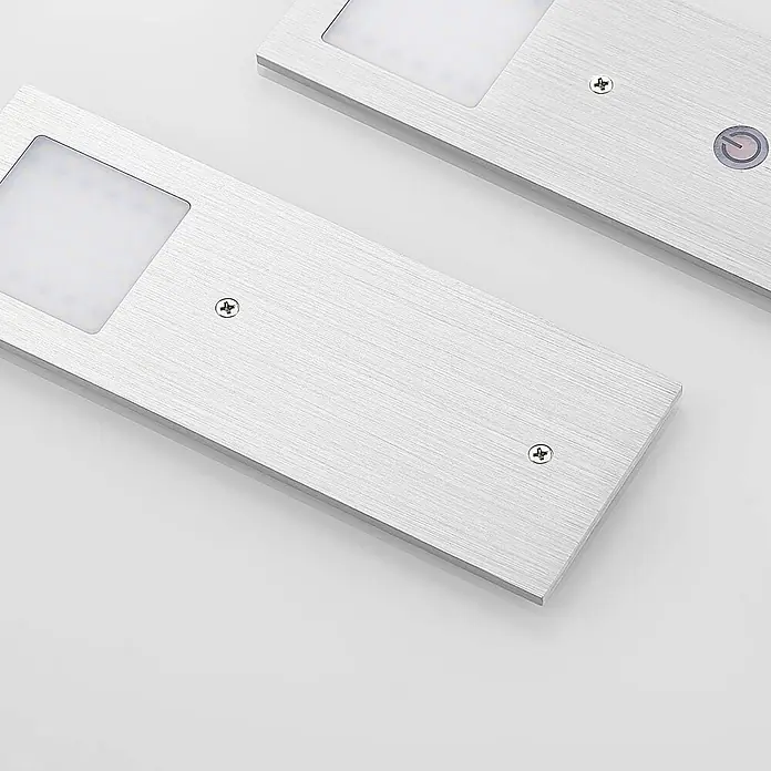 Arcchio LED-Unterbauleuchte Nortra -  - Zwei silberne LED-Lichtleisten aus gebürstetem Aluminium mit sichtbaren Schrauben, eine mit einem Einschaltknopf.