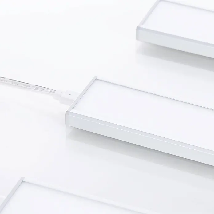 Prios LED-Unterbauleuchte Ashtonis - L x B x H: 20 x 4,2 x 1 cm - Weiße rechteckige LED-Lichtpaneele mit Aluminiumrahmen, durch ein weißes Kabel verbunden.