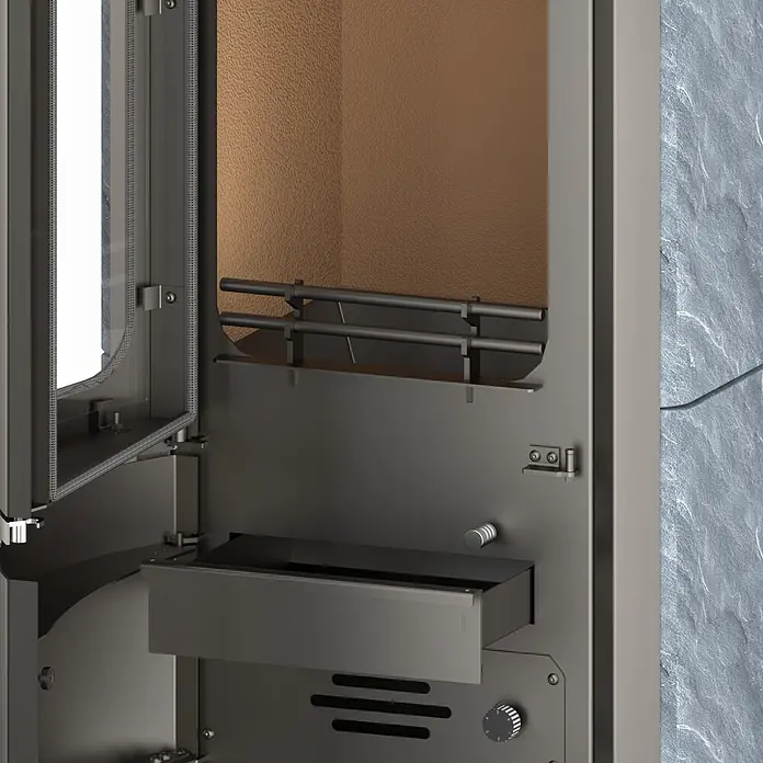 Kaminofen Prestige - 7 kW, Raumheizvermögen: 200 m³, Material Verkleidung: Speckstein - Nahaufnahme eines dunklen Metall-Kaminofens innen, mit teilweise offener Glastür, Rost, Ascheschale und Bedienknebel, vor einer Steinwand.