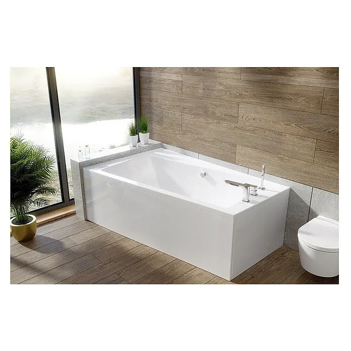 Bad Land Eckbadewanne INFINITY Acryl-Eckwanne 170 x 110 cm links Weiß, inkl. Styroporverkleidung - Sanitäracryl, Weiß - Weiße rechteckige Badewanne mit Chromarmaturen in einem modernen Badezimmer mit Holzoptik-Wänden und -Boden, beleuchtet von einem großen Fenster.