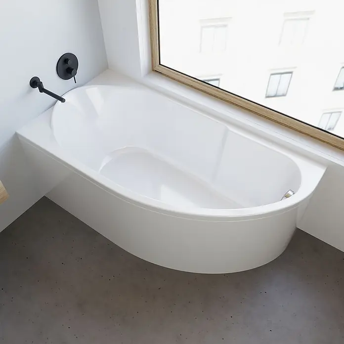 Bad Land Eckbadewanne MIKI Acryl-Eckwanne 145 x 85 cm links Weiß - Sanitäracryl, Weiß - Weiße Einbauwanne mit schwarzen Wandarmaturen am Fenster, auf Betonboden.