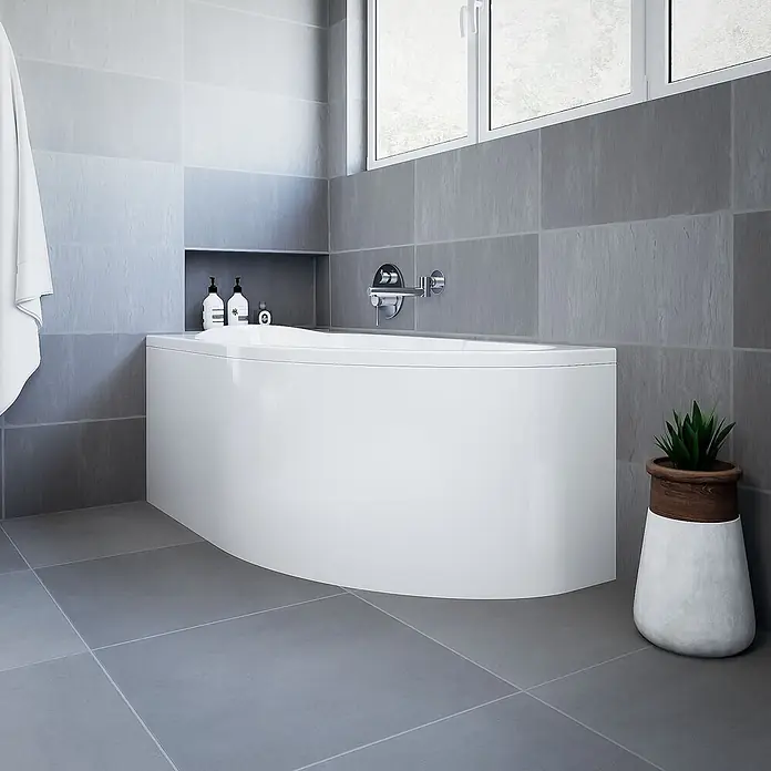 Bad Land Eckbadewanne MIKI Acryl-Eckwanne 140 x 70 cm links Weiß - Sanitäracryl, Weiß - Eine moderne, weiße, geschwungene Badewanne in einem Badezimmer mit grauen Fliesen, Nische und Fenster.