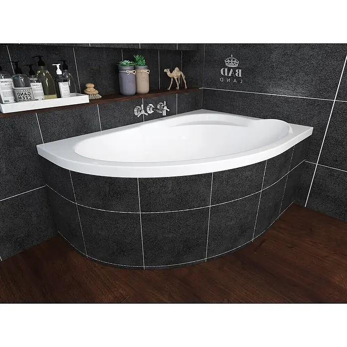 Bad Land Eckbadewanne STANDARD Acryl-Eckwanne 130 x 85 cm rechts Weiß - Sanitäracryl, Weiß - Weiße Eckbadewanne in Viertelkreisform mit dunkelgrauem Fliesensockel, in einem modernen Bad mit passenden Fliesen und Holzfußboden.