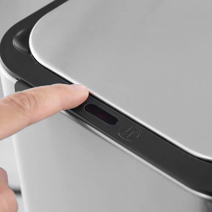 SVITA Sensormülleimer SE13L - 13 l, Edelstahl, Silber - Ein Finger drückt einen Sensor mit rotem Licht und Pfeilsymbol auf einem Deckel aus gebürstetem Edelstahl.