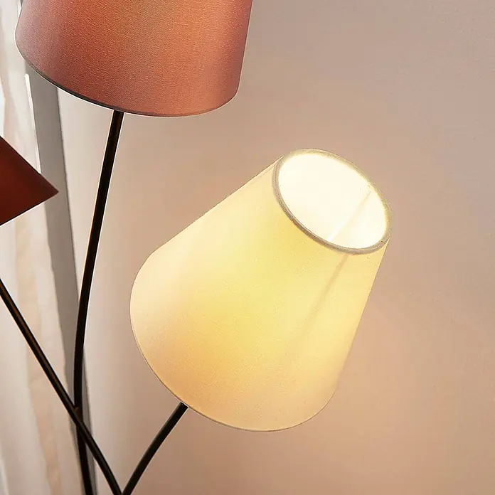 Lindby Stehleuchte Melis - creme / amber, E14 - Eine Stehleuchte mit mehreren Köpfen, dunklen Metallarmen und Textilschirmen. Ein cremefarbener Schirm leuchtet, ein anderer ist rotbraun.