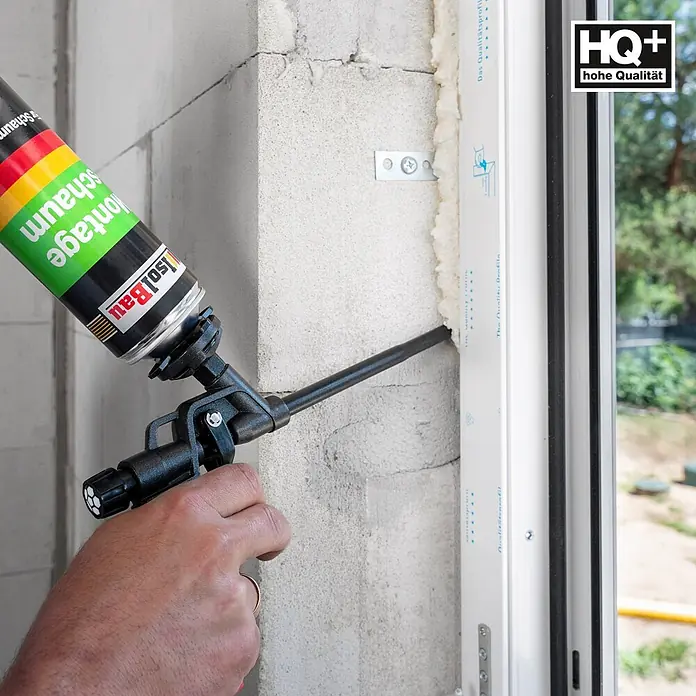 IsolBau Bauschaum 1 x Montageschaum 750 ml - 750 ml - Eine Person trägt mit einer Applikatorpistole IsoBau Montageschaum aus einer grün-schwarzen Dose auf, um eine Fensterfuge zu dichten.