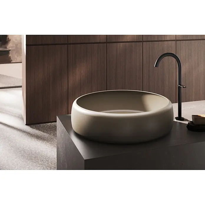 Bette Waschtisch -  - Runde greige Aufsatzwaschschale mit schwarzem geschwungenem Wasserhahn auf dunkler Theke in modernem Bad.