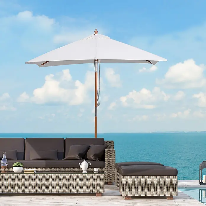 Outsunny Marktschirm - Weiß - Outdoor-Rattan-Lounge-Set mit dunklen Polstern und einem weißen Sonnenschirm auf einer Terrasse mit Meerblick.