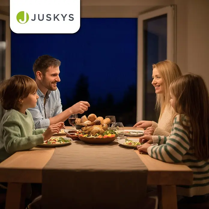 Juskys Insektenschutzfenster Fliegenschutzgitter - B x H: 120 x 140 cm, Montage Insektengitter: Klemmen - Familie genießt ein festliches Abendessen mit Brathähnchen und Salat an einem Holztisch in gemütlicher Atmosphäre.
