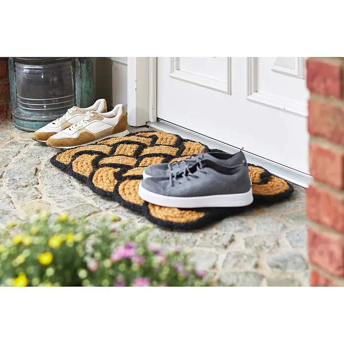 Fußmatte Nature Classic - 75 x 45 cm, Natur/Schwarz, Material Nutzschicht: 100 % Kokos - Eine gemusterte Kokosfasermatte in Schwarz und Naturbraun an einer Haustür, mit zwei Paar Schuhen davor.