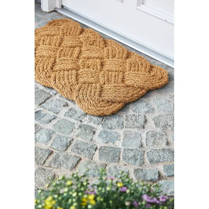 Fußmatte Nature Classic - 75 x 45 cm, Natur, Material Nutzschicht: 100 % Kokos - Brauner Kokos-Fussabtreter mit Korbmuster auf Steinboden vor einer weißen Tür.
