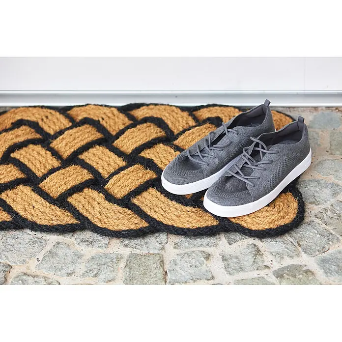 Fußmatte Nature Classic - 75 x 45 cm, Natur/Schwarz, Material Nutzschicht: 100 % Kokos - Ein Paar graue Strick-Sneaker mit weißen Sohlen und grauen Schnürsenkeln liegt auf einer geflochtenen Kokos-Fußmatte.