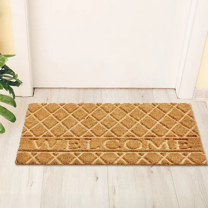 Fußmatte Coco Shape - 75 x 45 cm, Natur, Material Nutzschicht: 100 % Kokos, Welcome - Braune Kokos-Fußmatte mit Rautenmuster und "WELCOME"-Schriftzug vor einer Tür auf hellem Boden.