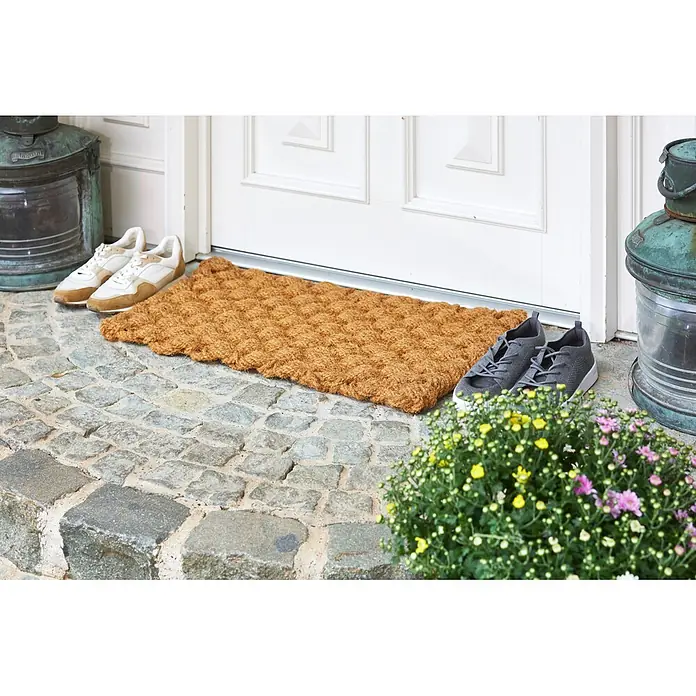 Fußmatte Nature Classic - 75 x 45 cm, Natur, Material Nutzschicht: 100 % Kokos, Karo - Naturbraune Kokosfasermatte mit strukturierter Oberfläche, vor einer weißen Tür auf Kopfsteinpflaster platziert.
