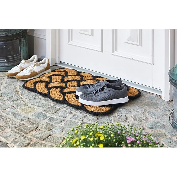 Fußmatte Nature Classic - 75 x 45 cm, Natur/Schwarz, Material Nutzschicht: 100 % Kokos - Braune und schwarze gewebte Fußmatte vor einer Tür mit Schuhen darauf und daneben.