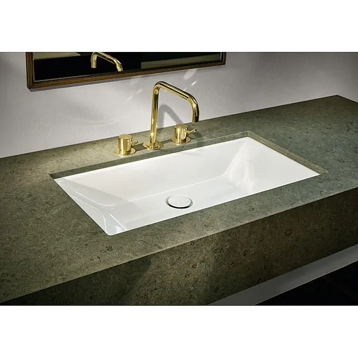 Bette Unterbauwaschbecken -  - Weißes, rechteckiges Einbauspülbecken mit goldenem Wasserhahn und Griffen in dunkler, strukturierter Arbeitsplatte.