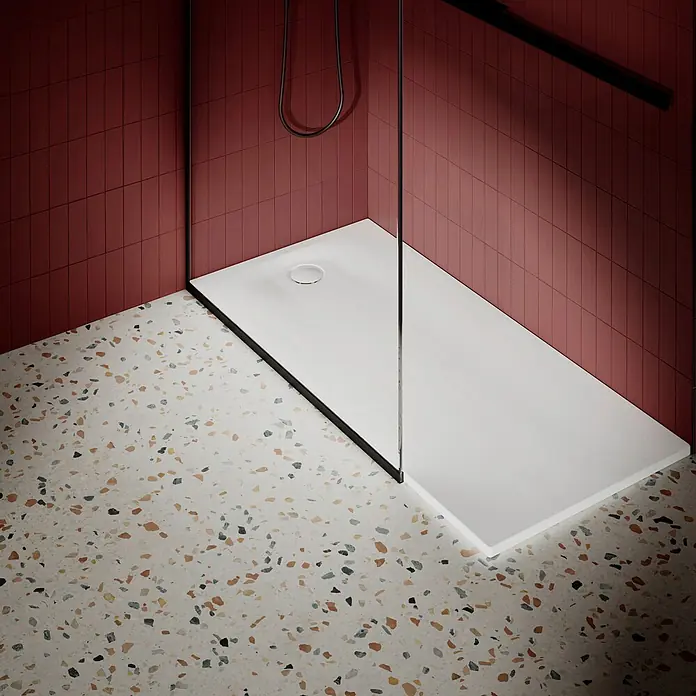 Bette Duschwanne -  - Moderne Dusche mit schlanker weißer Duschwanne, Glasabtrennung und dunkelroten Fliesen auf Terrazzoboden.