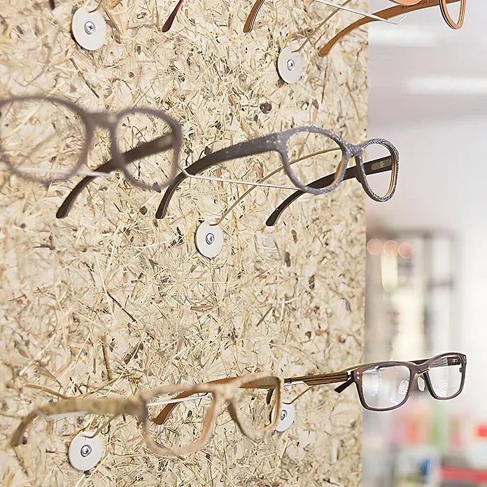Wallface Wandpaneel AL-11001 ALPINE PURE selbstklebend Almwiesen-Dekor braun 4 m2 - beige, 3.050 x 1.360 mm - Verschiedene Brillen mit unterschiedlichen Fassungen an einer natürlichen, texturierten Wand ausgestellt.