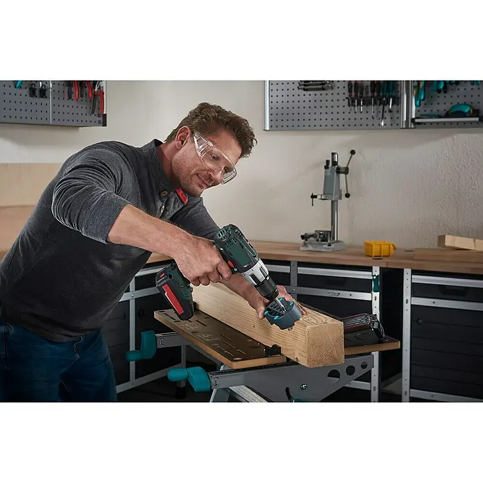 Wolfcraft Bohrhilfe - Durchmesser Bohrer: 4 mm - 10 mm - Ein Mann bohrt mit einer Wolfcraft Bohrmaschine in ein Holzstück. Er trägt dabei eine Schutzbrille für die Sicherheit.
