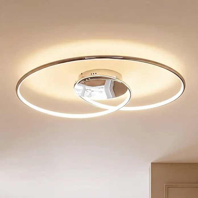 Lindby Deckenleuchte Joline - chrom / silber - Moderne LED-Deckenleuchte mit großem Chromring und zwei verschlungenen Lichtringen, die warmes Licht an eine helle Decke wirft.
